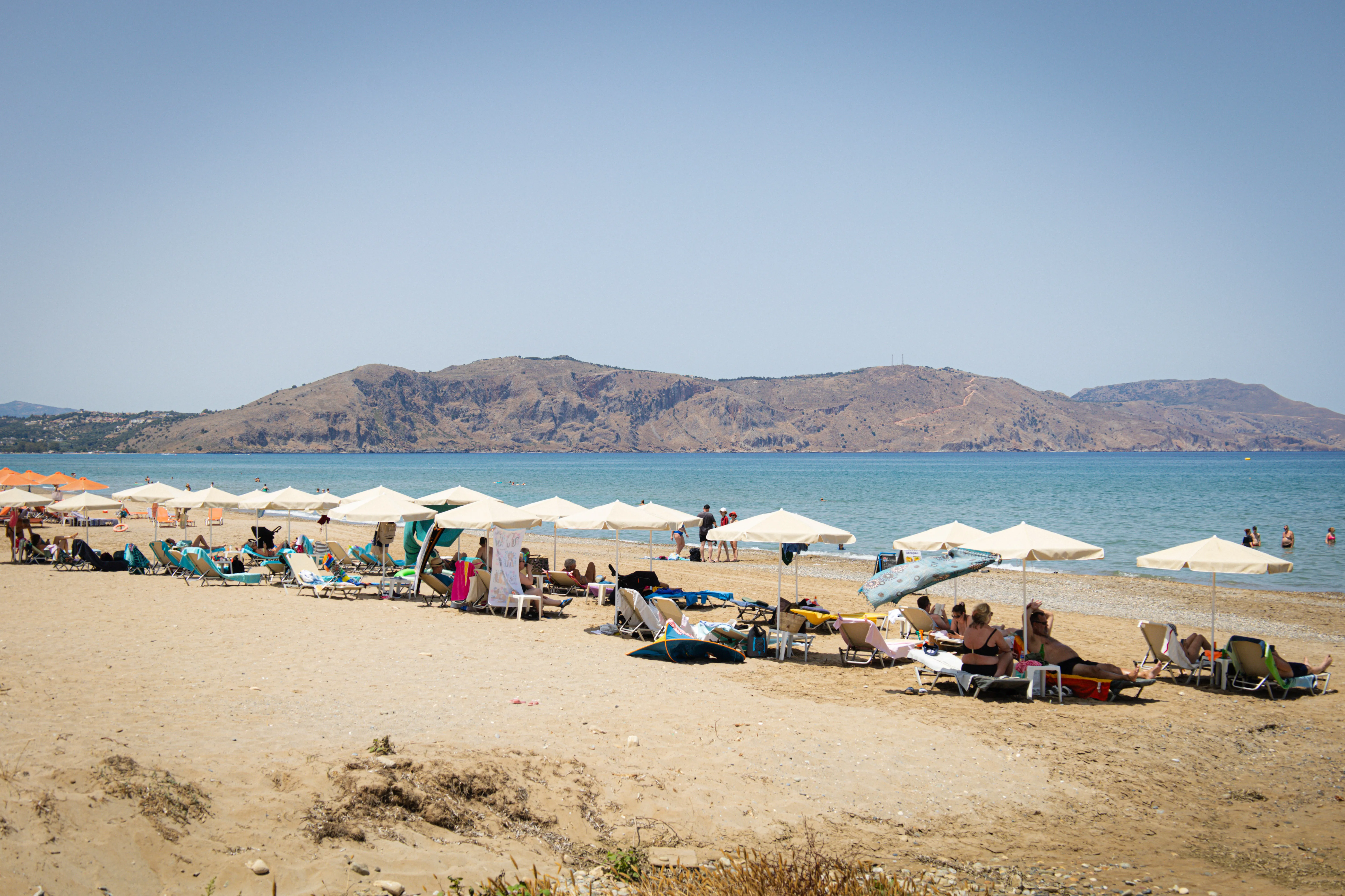 Reihen von Sonnenschirmen und Liegen am Kournas Beach, Meer bis zum Horizont